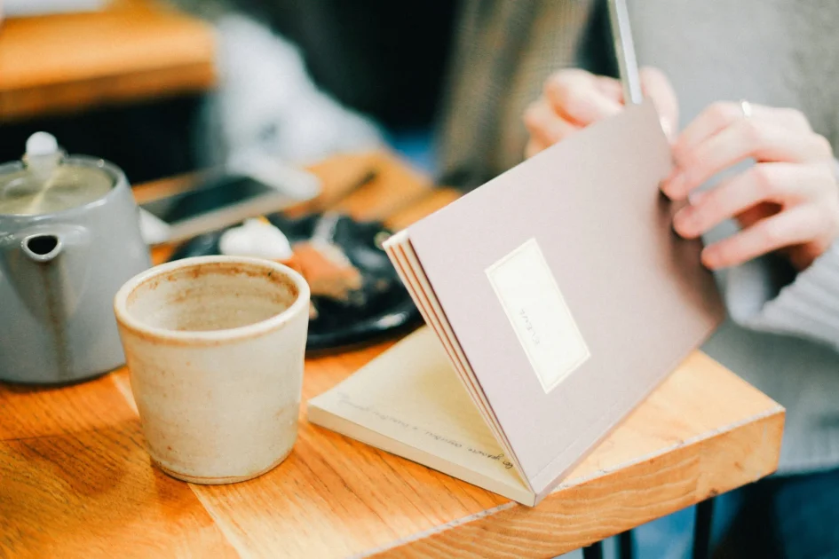 Person writing in a journal beside a cup of coffee, symbolizing reflection, memory, and dream interpretation