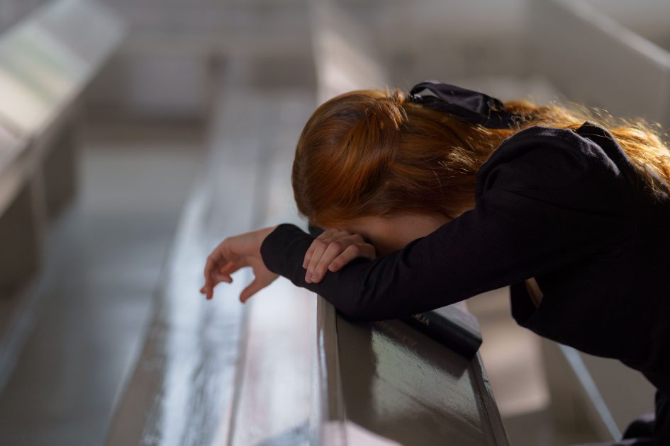 A woman with her head down and praying | Image Source: Pexels
